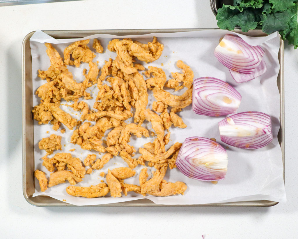 Red onion and soy curls on a baking tray.