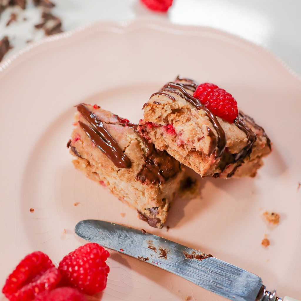 Dark chocolate raspberry scone, cut in half on a pink plate.