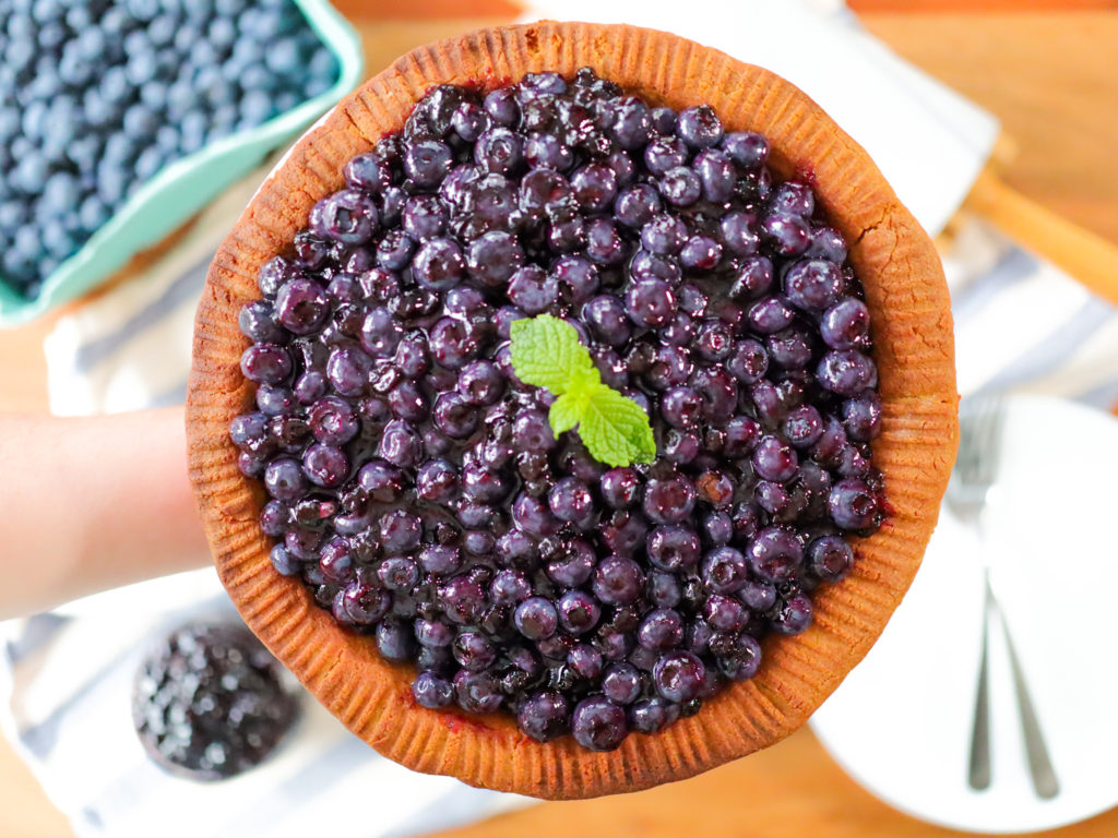 hand holding a blueberry pie