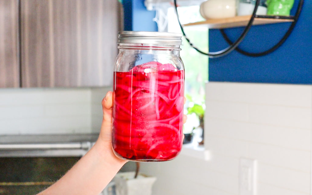 hand holding a jar of pickled red onions 